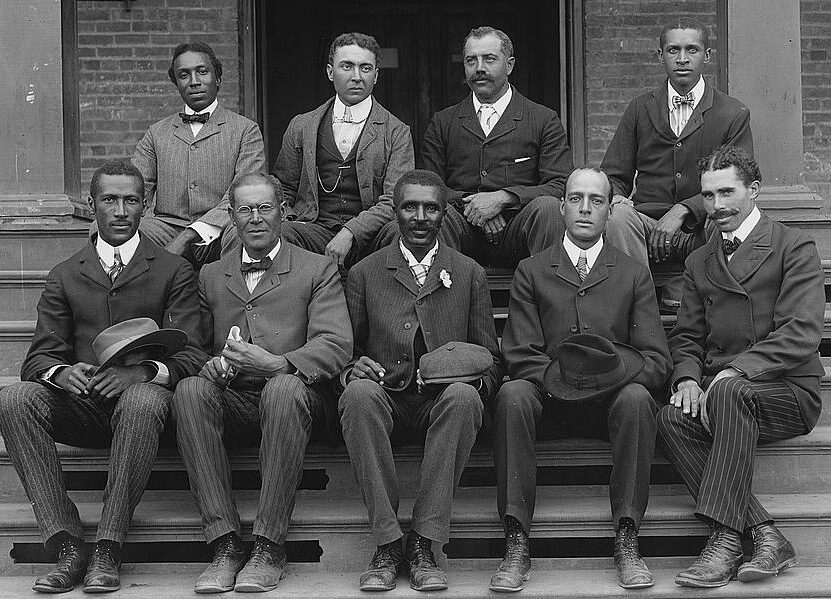 George Washington Carver seated (front row, center) on steps at the Tuskegee Normal and Industrial Institute, with staff, ca. 1902.