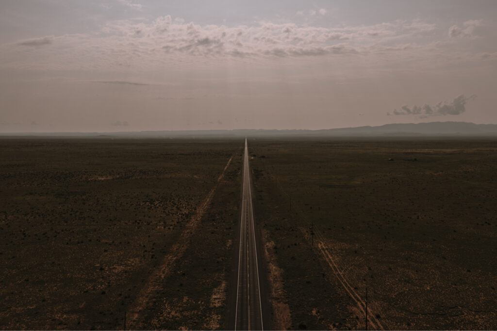 Wide landscape photo of a straight empty highway in the desert